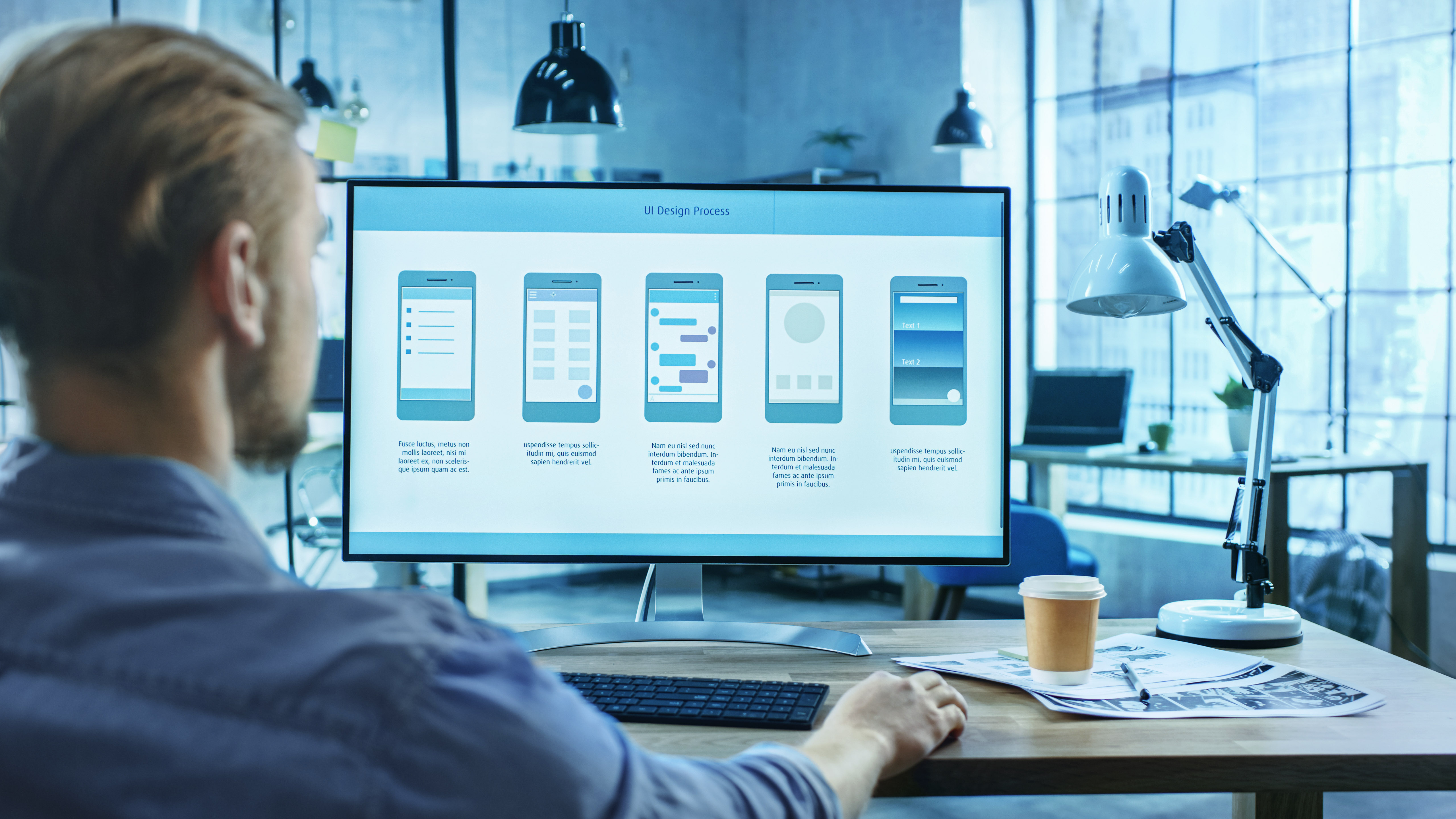 UI-Designer evaluiert Benutzeroberflächen auf einem großen Bildschirm, Prozess der digitalen Produktgestaltung.
